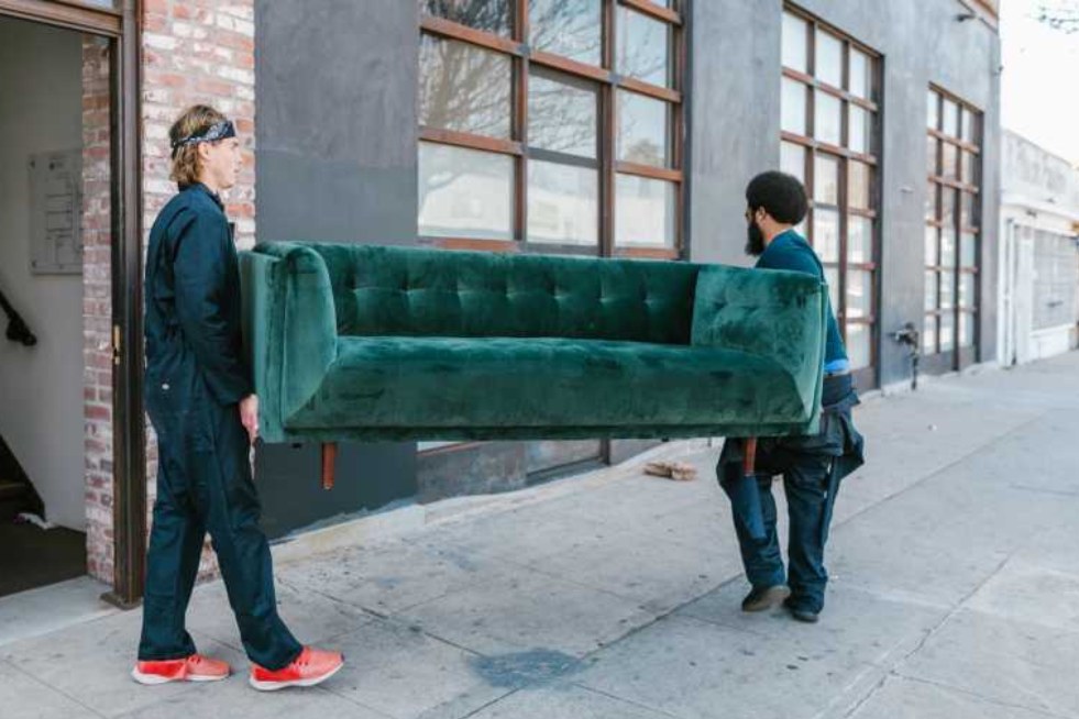 two men carrying a green couch