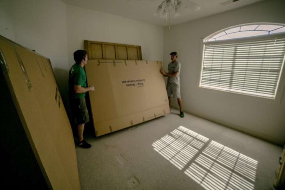 two men holding a large cardboard box