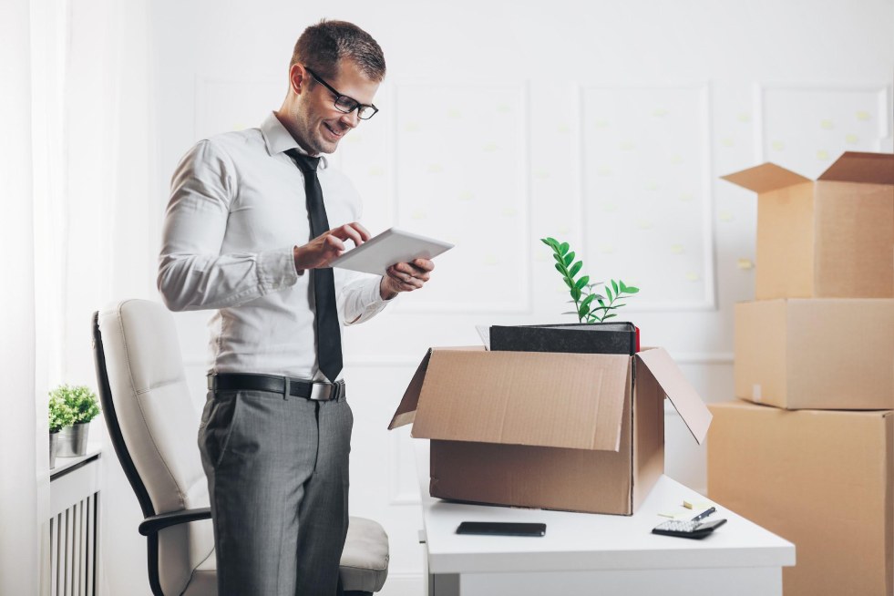 a man is smiling and standing in front of a cardboard box