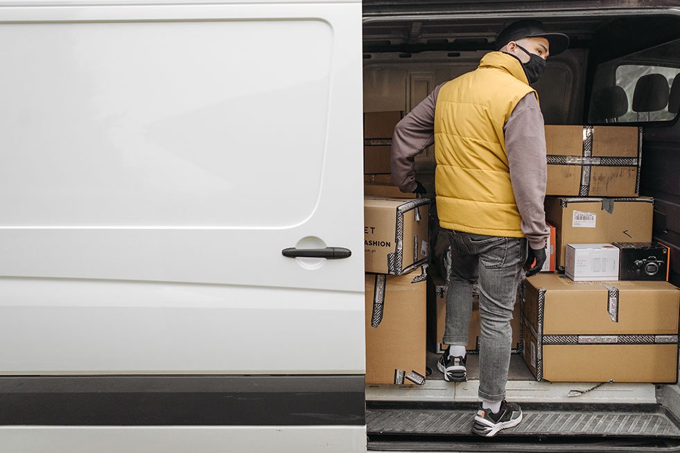 a man wearing a mask and standing in a van with boxes