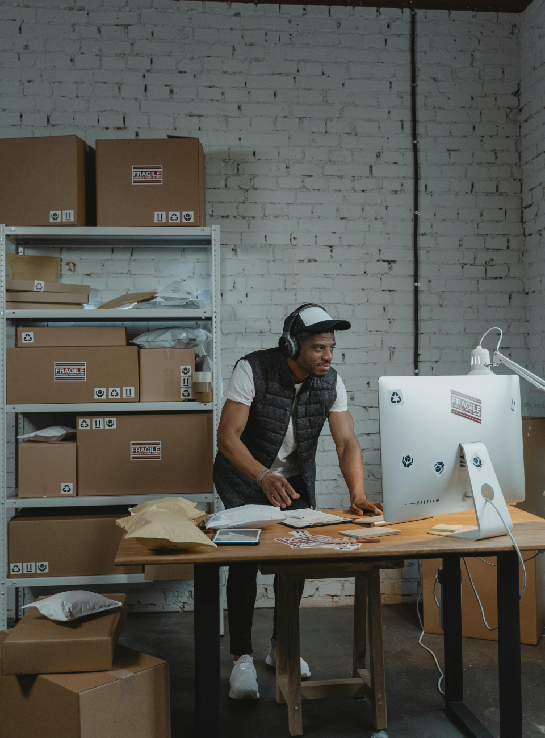 a man wearing headphones and a vest standing in front of a computer