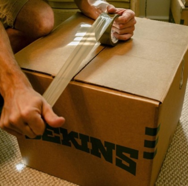 a man is closing a box with tape