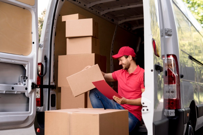 a man in red t-shirt and red cap smiling while looking at a box