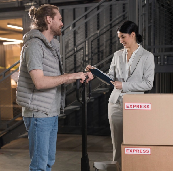 A man talking to a woman who is standing besides some cardboard boxes