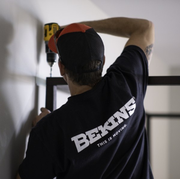 a man is wearing black Bekins T-shirt and drilling