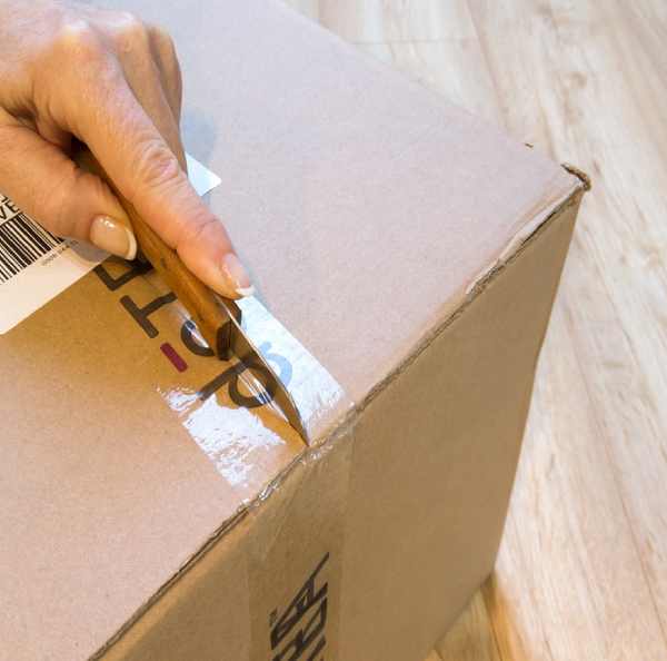 a hand holding a sticker on a cardboard box