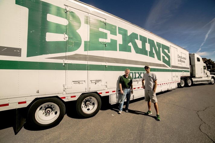 two men standing next to a truck