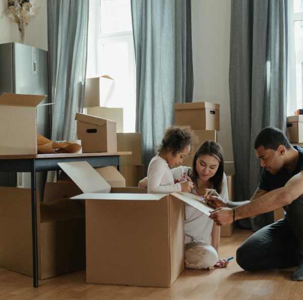 a man and woman sitting on the floor with a child and a cardboard box